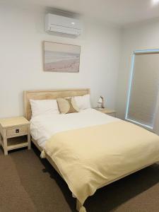 a bedroom with a large white bed and a window at Brand New House in Lakes Entrance in Lakes Entrance