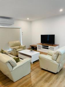 a living room with white furniture and a flat screen tv at Brand New House in Lakes Entrance in Lakes Entrance