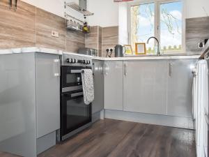 a kitchen with white cabinets and a black oven at Sycamore Cottage in Broomhill