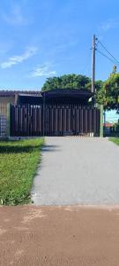 a building with a wooden fence next to a sidewalk at Linda Kit Net Mobiliada Individual in Dourados