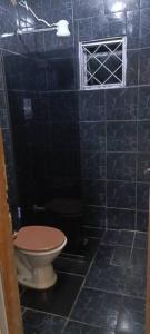 uma casa de banho em azulejos azuis com um WC e uma janela em Linda Kit Net Mobiliada Individual em Dourados