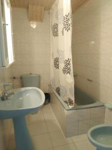 een badkamer met een wastafel, een bad en een douchegordijn bij 3 bedroom house near beach lighthouse hiking trail in Corme-Puerto