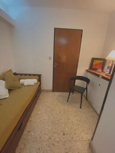 a bedroom with a bed and a chair and a door at Sol del Valle in San Fernando del Valle de Catamarca
