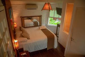 a bedroom with a bed with a large mirror at alua pousada ventos de camburi in Camburi