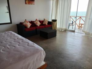 1 dormitorio con sofá rojo y vistas al océano en Casa de Playa Akas, en Canoas de Punta Sal