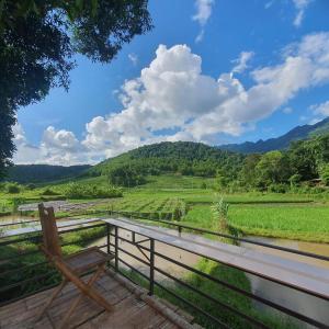 a wooden bench sitting on a deck overlooking a field at Quế Homestay in Hòa Bình