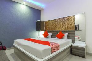 1 dormitorio con 1 cama blanca grande con almohadas de color naranja en Flagship Aashirwad Guest House, en Ranchi