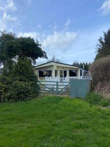 a house with a fence in front of a yard at Beautiful Rural Holiday Chalet in Lincolnshire