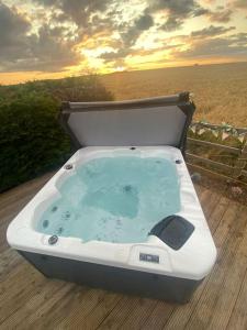 a bath tub on a deck with the sunset in the background at Beautiful Scenic Holiday Chalet in Lincolnshire