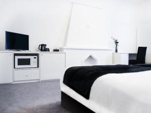 a white bedroom with a bed and a tv at Hotel Satellite in Brussels