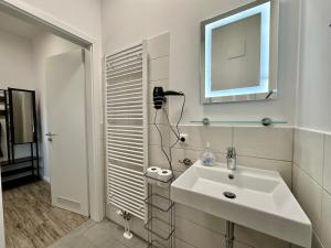 a white bathroom with a sink and a mirror at Haus Concordia 2 Phönix in Thiessow +40 photos