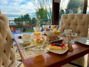 einen Tisch mit einem Frühstück mit Kuchen und Obst in der Unterkunft Borde Luz Hotel Boutique in Pucón