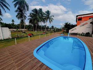 una gran piscina en una terraza de madera con palmeras en Pousada Xaréu Maragogi, en Maragogi