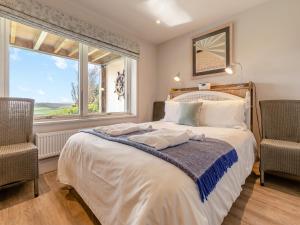 a bedroom with a bed with two chairs and a window at Long Commons in Saint Mawes