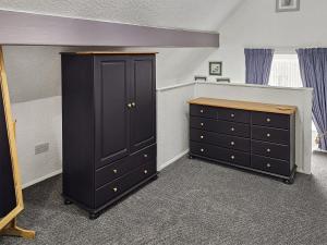 a bedroom with a black cabinet and a dresser at Stable Cottage - 29155 in Staintondale