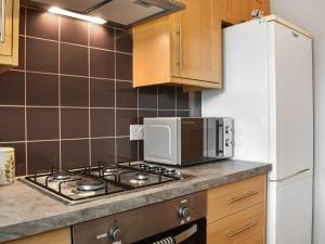 a kitchen with a stove and a microwave at Cowie Mill Apartment in Stonehaven