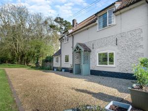 ein weißes Haus mit einer Einfahrt davor in der Unterkunft Little Crawfish Cottage in Thursford