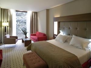 una habitación de hotel con una cama grande y una silla roja en Gran Hotel Las Caldas by blau hotels - Adults Only, en Las Caldas