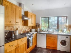 a kitchen with wooden cabinets and a washer and dryer at The Yellow House in Gorleston-on-Sea