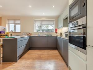 a kitchen with gray cabinets and a stove top oven at Little Hill Farm Villa in Ringwood