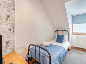 Dormitorio pequeño con cama con almohada azul en Coire Cas - S4538, en Aviemore