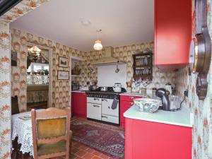 a kitchen with red cabinets and a white stove at St Marys Chambers in Mold
