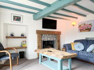 a living room with a table and a fireplace at Holly Cottage in Ashover