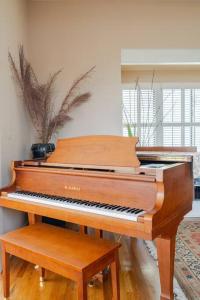 a brown piano sitting in a living room with a bench at Dreamy 3-Story House : Sunroom + City Skyline View in San Francisco
