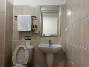 a bathroom with a toilet and a sink and a mirror at Grand Riviera Suites in Manila