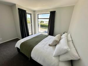 ein Schlafzimmer mit einem Bett und einem großen Fenster in der Unterkunft Stylish 3-bed Taradale Townhouse in Napier
