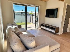 ein Wohnzimmer mit einem Sofa und einem Flachbild-TV in der Unterkunft Stylish 3-bed Taradale Townhouse in Napier