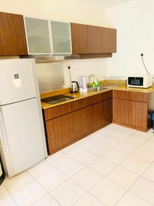 クアラルンプールにあるCool And Cozy Home By Seri Bukit Ceylon Residencyのキッチン(木製キャビネット、白い冷蔵庫付)