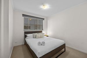 een slaapkamer met een bed met twee slippers erop bij South Vale Apartments South Brisbane in Brisbane