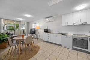 een keuken met witte kasten en een tafel en stoelen bij South Vale Apartments South Brisbane in Brisbane