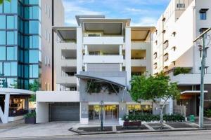 een groot wit gebouw met een parkeerplaats bij South Vale Apartments South Brisbane in Brisbane