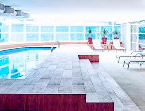 聖保羅的住宿－Hotel M-RCURE - Av Paulista - GRAND PLAZA - Deluxe king Studio Veranda - BATH SPA - Executive Class - By LuXXoR，一座带桌椅的游泳池