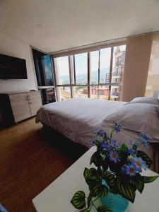 - une chambre avec un lit et une table ornée d'un vase de fleurs dans l'établissement SoHo 902 con parqueadero cubierto WIFI 5G, à Armenia