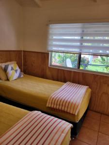1 dormitorio con 2 camas y una ventana con persianas en Hostal Raioha, en Hanga Roa
