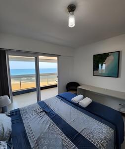 a bedroom with a bed with a view of the beach at Vista Mar Apartamento em Armação in Salvador