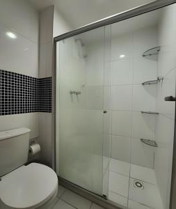 a bathroom with a toilet and a glass shower at Vista Mar Apartamento em Armação in Salvador