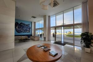 uma sala de estar com uma mesa de madeira e uma grande janela em Vista Mar Apartamento em Armação em Salvador