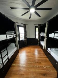 a room with four bunk beds and a ceiling fan at Howzit Hostels Hawaii in Hilo