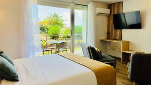a hotel room with a bed and a balcony with a television at Studio neuf et cosy proche des plages - L'Alamanda in Le Gosier +9 photos