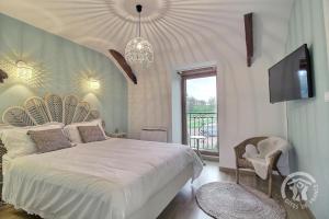 1 dormitorio con 1 cama, TV y lámpara de araña en La vallee de leber, en Plouasne