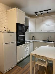a kitchen with white appliances and a table with chairs at Квартира в центре Алматы in Almaty