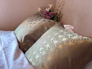 two pillows on a bed with a vase of flowers at 京都駅そばの一棟貸し京町家 suiten shichijo 萃点七条 in Kyoto