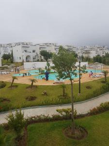 a swimming pool in a park with a tree at Résidence Al Cudia Smir - Plage Riffiyenne in Fnidek