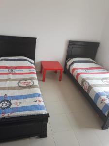 duas camas num quarto com uma mesa vermelha em Résidence Al Cudia Smir - Plage Riffiyenne em Fnideq