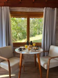 a dining room with a table and two chairs and a window at Chalé Recanto das Estrelas in Monte Verde