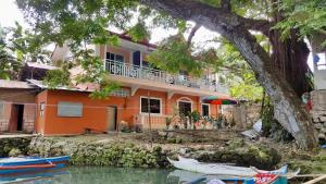 a house on the water with boats in front of it at TGH Guest House Badian in Badian